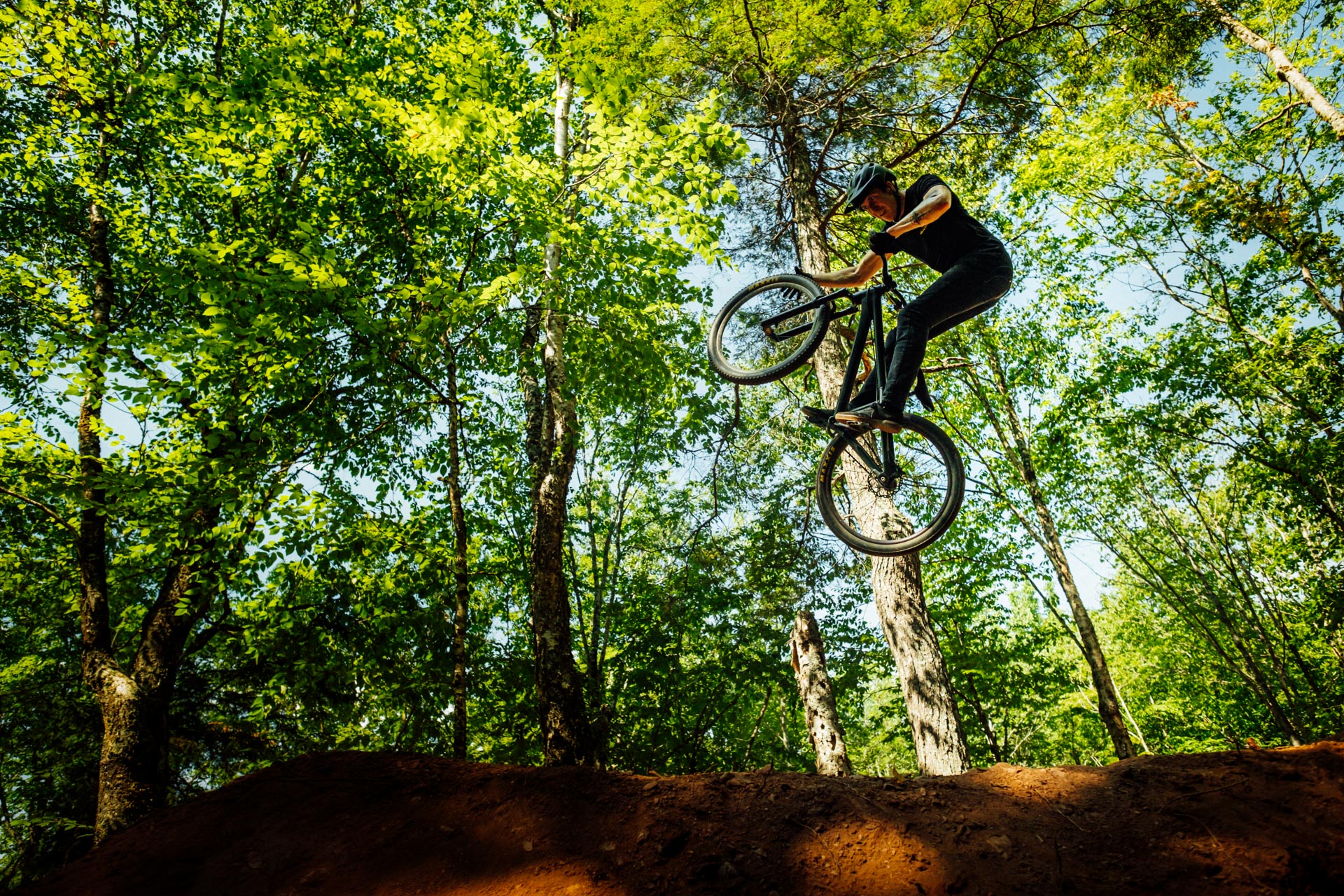 Devon White doing a wheel grab at the Callus jump line at the Truro Railyard trails.